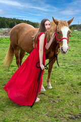 A young woman in a red dress with a horse