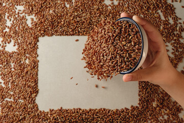 Hand pouring organic brown rice into a decorative arrangement on paper