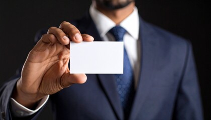 Office worker holding a horizontal business card, black background, strict business style, focus on hands and card.