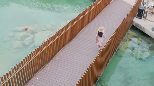 Aerial drone view of a woman walking on a wooden bridge over a scenic canal with teal water -4k pro ress 422 travel stock videos 