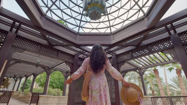 young happy woman twirling with open arms under a palace dome in a beautiful flowy floral dress 