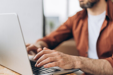 Freelancer working remotely from home office typing on laptop keyboard selective focus on hands