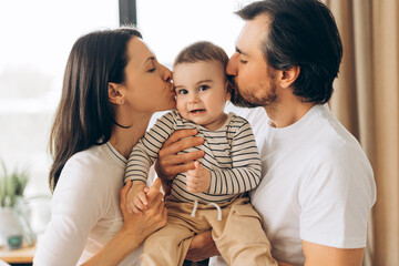 Happy parents kissing their baby son at home