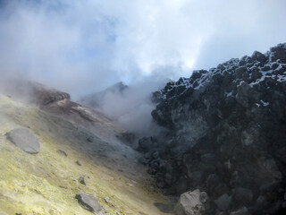 View of a steaming volcanic plug with sulfur deposits inside Avachinsky volcano crater on Kamchatka Peninsula. Harsh geothermal environment and otherworldly terrain.