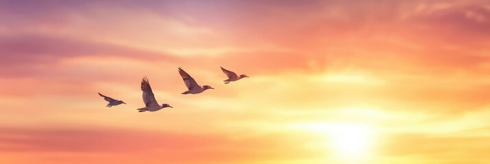 Fototapeta premium A captivating view of birds in V formation gliding across a sunset sky. The harmonious sky transitions from lavender to peach, adorned with pink-tinged clouds, creating an ethereal scene.
