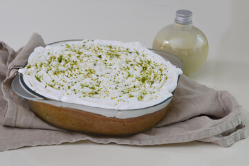 Key Lime Pie in a clear glass baking dish topped with white whipped cream with bright green lime...