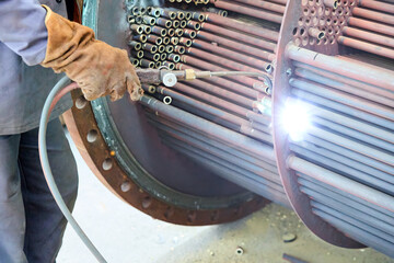 Close-up of industrial flame cutting of copper heat exchanger tubes in a thermal power plant. Ideal for: energy production, industrial maintenance, engineering, power infrastructure topics.