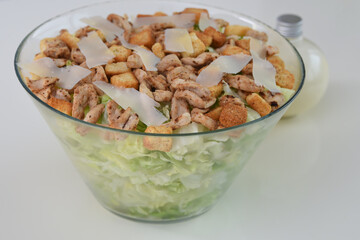 Classic Chicken Caesar Salad in a clear glass bowl with crisp lettuce, tender grilled chicken pieces, croutons, and Parmesan cheese side view of healthy salad