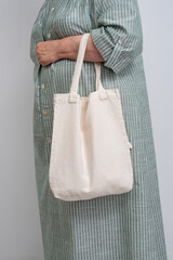 Anonymous woman holding a beige reusable shopping bag. Shopper