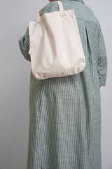 Anonymous woman holding a beige reusable shopping bag. Shopper