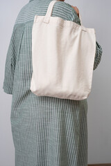 Anonymous woman holding a beige reusable shopping bag. Shopper