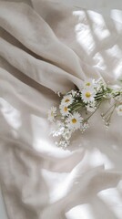 Fresh daisies arranged delicately on a soft linen fabric in natural light during the morning