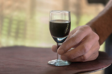 Man's hand holding a glass of red wine on a blurred background