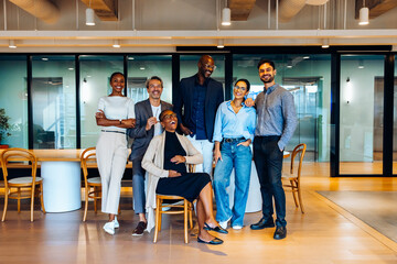 Group of professionals posing confidently in a well-lit contemporary office interior looking at the...