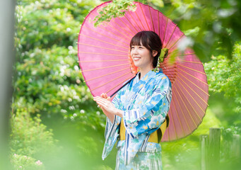 新緑の公園を歩く着物姿の若い女性