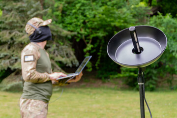 Modern espionage techniques: a military man with equipment in camouflage in the green zone.