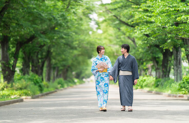 浴衣で並木道を散歩する浴衣カップル	