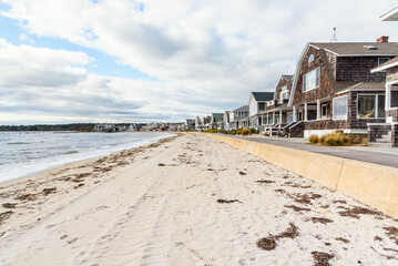 Traditional American wooden houses along a deserted sandy beach on a cloudy autumn day