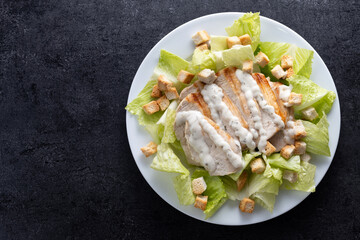 Classic Caesar Salad Fresh and crunchy Caesar salad on black slate background. Top view. Copy space