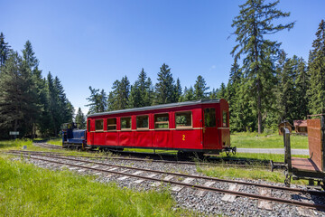 Red narrow gauge railway wagon standing on tracks in Pribylina, Slovakia, during summer sunny day