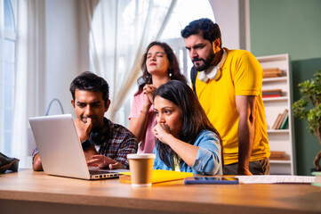 Students anxiously waiting for college result with laptop and friends in academic indoor setting
