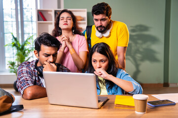 Fototapeta premium Students anxiously waiting for college result with laptop and friends in academic indoor setting