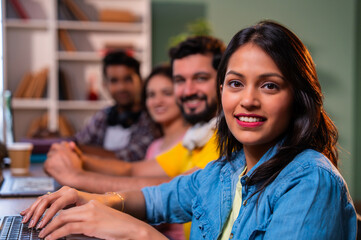 Completing group assignment happily, Indian college students collaborate in friendly library setting