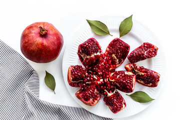 Top view of fresh ripe pomegranate and pieces on plate for eating, top view.