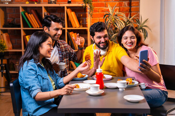 Taking video call with samosa snack, Indian students interact online in a cheerful cafe moment