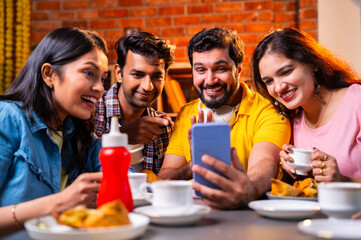 Taking video call with samosa snack, Indian students interact online in a cheerful cafe moment