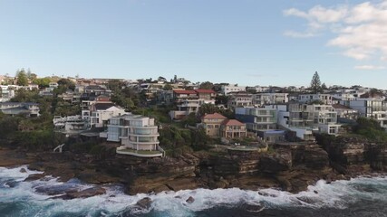 Aerial slide right of luxury cliffside home with ocean views – upscale waterfront property in Sydney’s Eastern Suburbs, Australia.