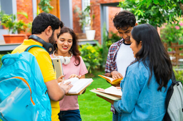 Indian university classmates standing outdoors in garden, collaborating and sharing ideas together