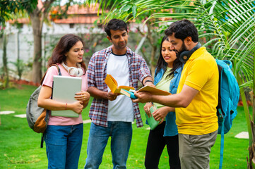 Indian university classmates standing outdoors in garden, collaborating and sharing ideas together