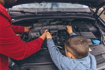 Father and sons repairing car together with the hood open. A heartfelt moment of bonding,...
