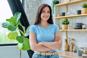 Portrait young smiling woman at home in kitchen