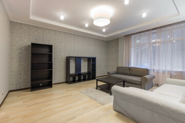 Fototapeta premium Spacious living room with a beautiful interior design. Fluffy carpet on the floor, elegant sofas. Window with tulle curtains.