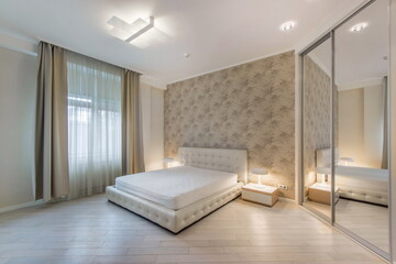 The interior of the bedroom is in pastel colors with an elegant design. Built-in wardrobe with sliding mirrored doors, light beige furniture.