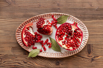 Plate full of fresh ripe pomegranate with cut in half and pieces, top view.