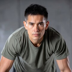 Army fitness test concept, A focused man in a green t-shirt leans forward, gazing intensely at the camera against a neutral background.