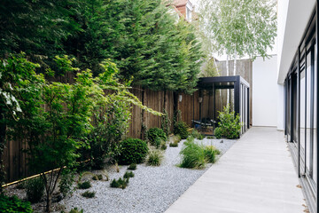 A beautiful walkway leads to a house amid lush trees and vibrant bushes