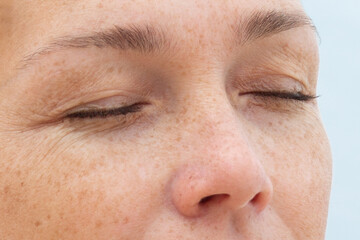 Woman face with closed eyes showing natural skin and wrinkles around the eyes