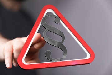 Hand points to a 3D red triangle warning sign with a paragraph symbol.  Legal concept.