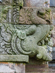 Closeup vertical view of makara head stone carving on ancient hindu Gedong Songo I temple wall Bandungan, Semarang, Java, Indonesia
