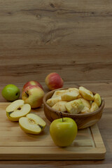 Fresh whole and peeled apples in a wooden bowl and on a cutting board. Natural fruit preparation...