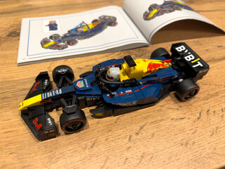 Naklejka premium Moscow, Russia, April 26, 2025: Completed LEGO Speed Champions model of the 2024 Red Bull Racing Formula 1 car with mini figure driver, shown next to instruction manual on wooden surface