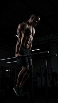 Muscular man performing exercise on parallel bars in gym setting