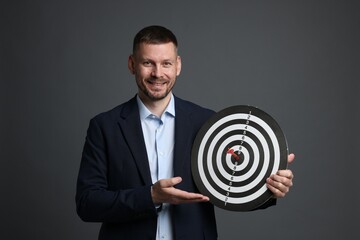 Targeting. Man with dart board and arrow on grey background
