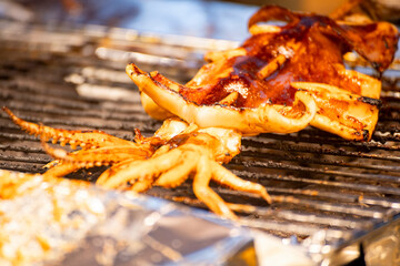  fresh squids is being grilled to a golden perfection on the barbecue grill