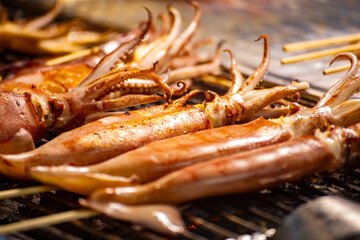  fresh squids is being grilled to a golden perfection on the barbecue grill