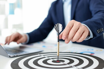 Man with dart aiming at dartboard while working indoors, closeup